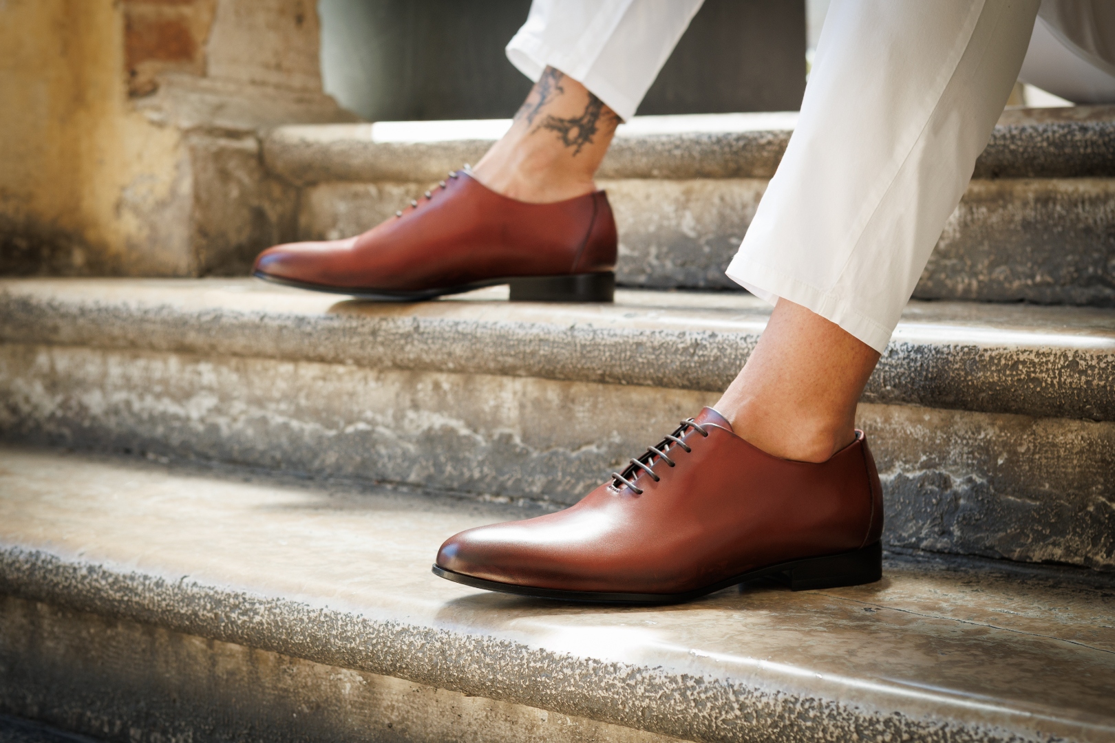 Nunzio Orsini maroon top grain Italian leather Oxford shoes worn casually on stone steps in Marche, Italy